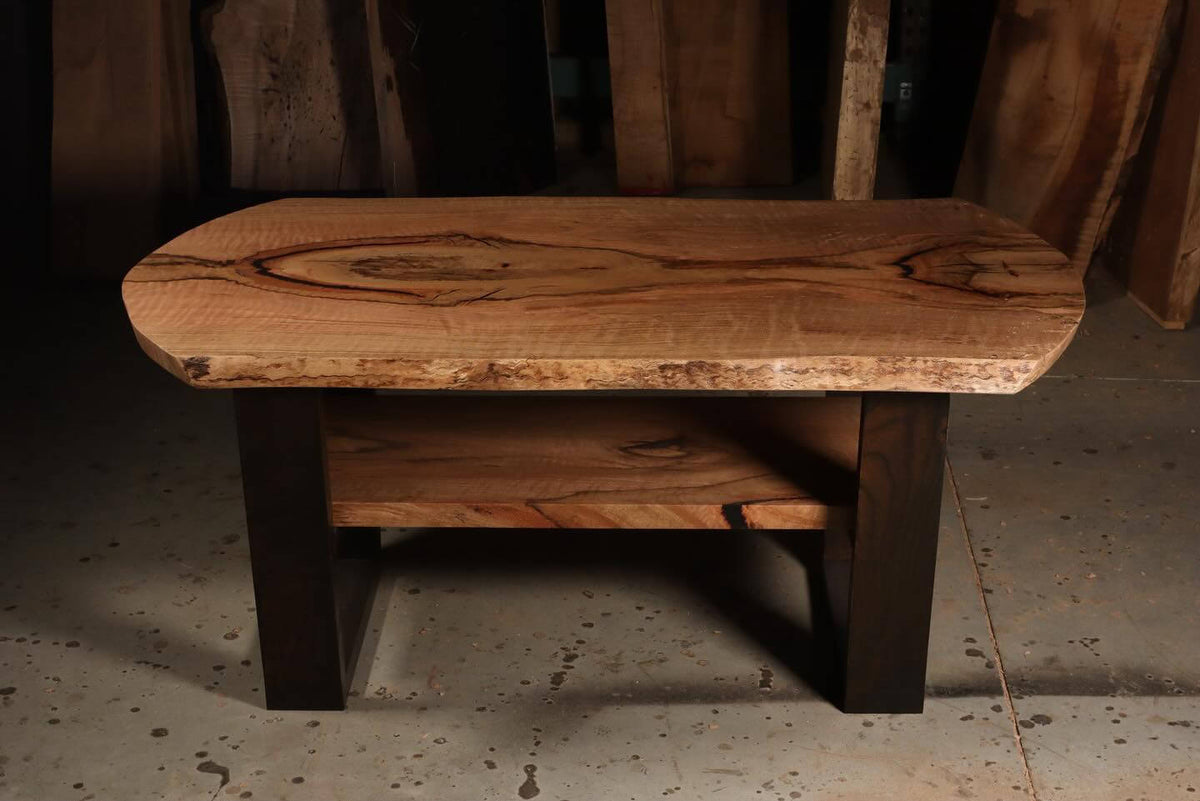 Rustic wooden coffee table with natural wood grain, featuring a sturdy design and dark legs, set in a workshop environment.