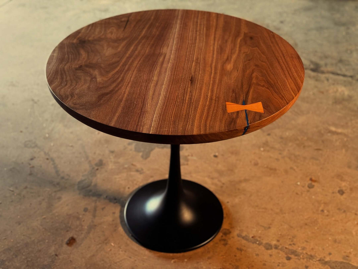 Modern round parlor table with solid hardwood top and black satin metal tulip base, elegant design for living spaces