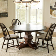 Dining room with a round wooden table and four chairs in a well-lit room.