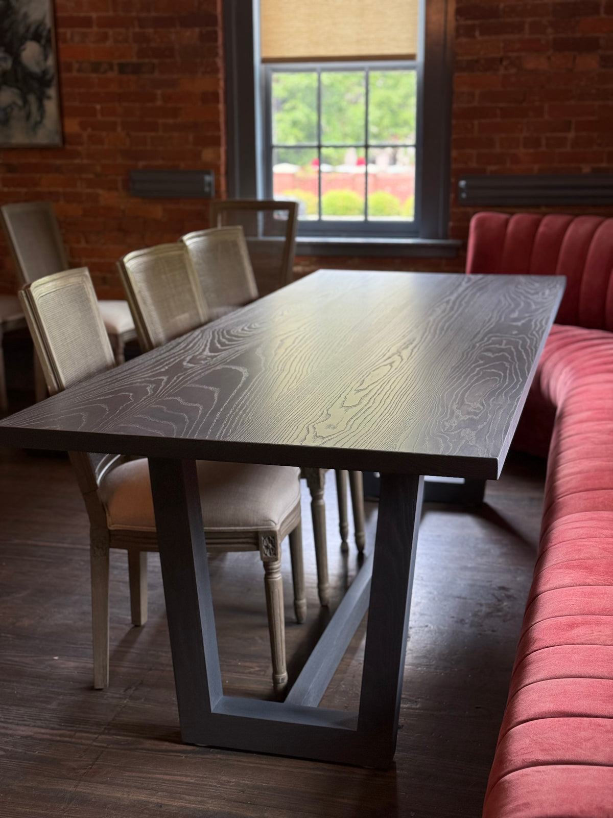 Dining table with chairs in a room with brick walls and a window.