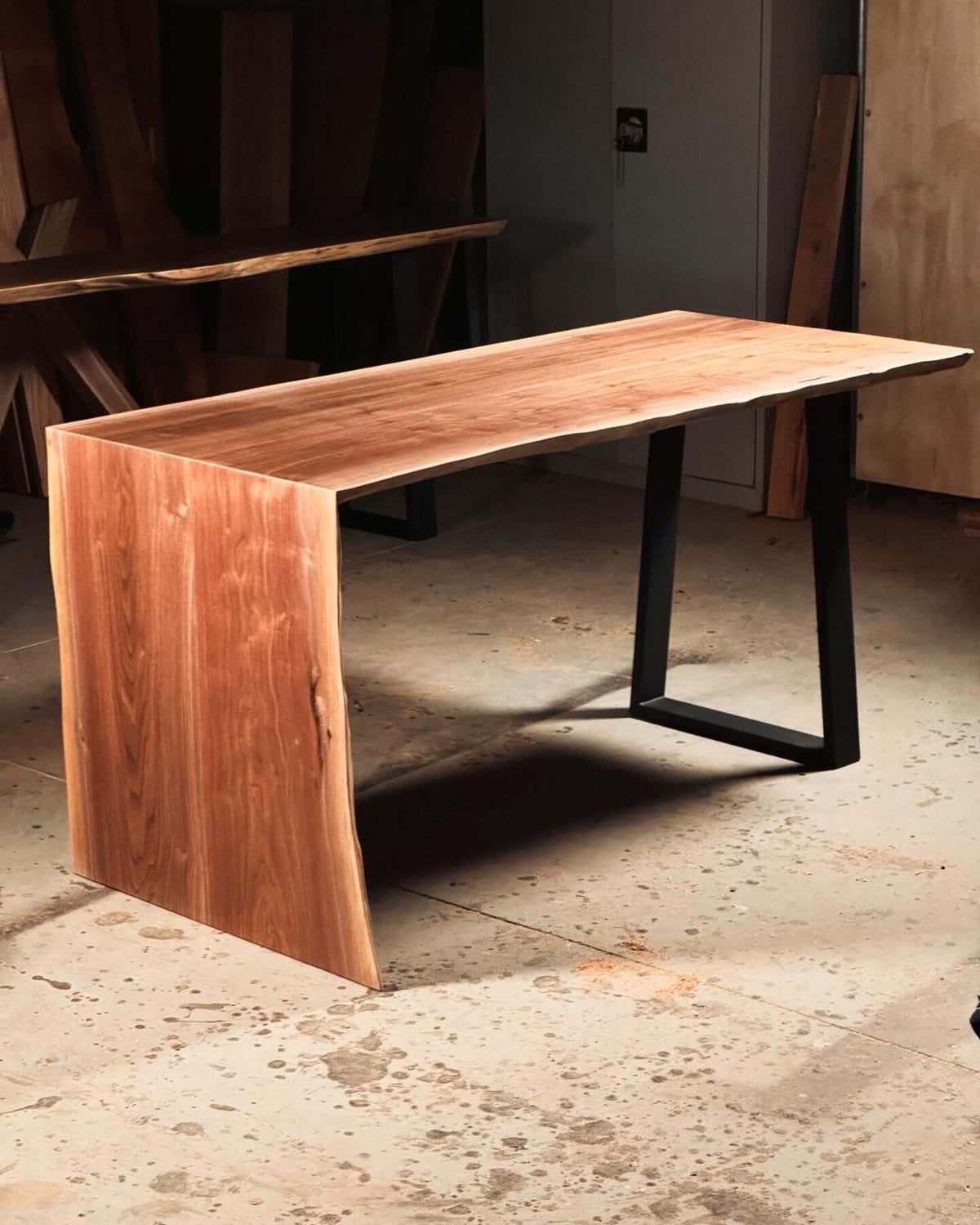 Live edge waterfall desk with seamless design in wooden finish, showcased in a room setting.