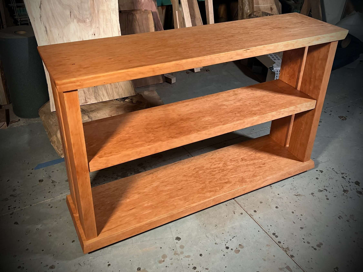 Solid cherry bookcase designed for vinyl records, showcasing wood tones and sturdy construction in a simple, elegant style.