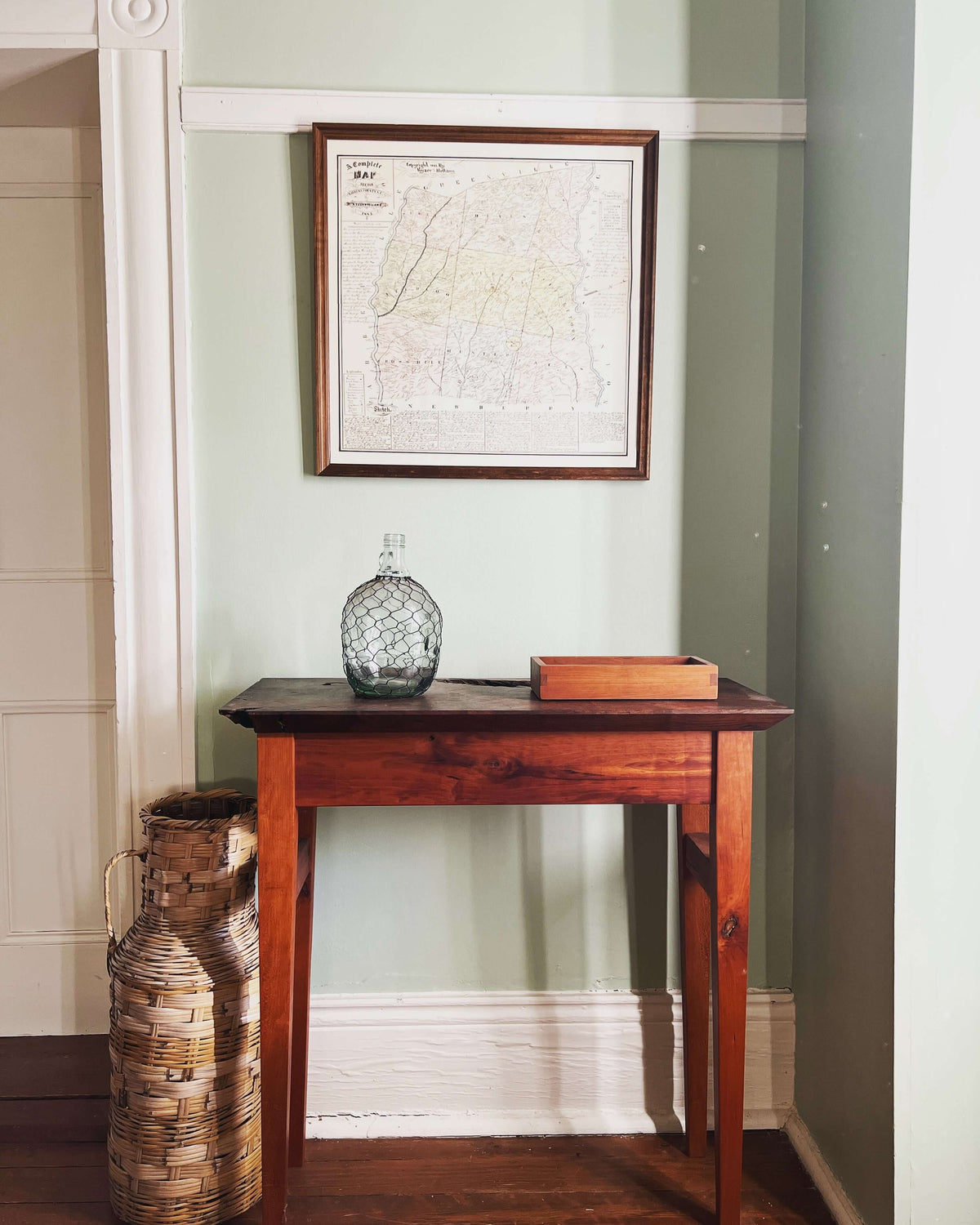 Elegant solid wood hall table with decor, framed map on wall, in a classic entryway setting. Perfect for storage and display.