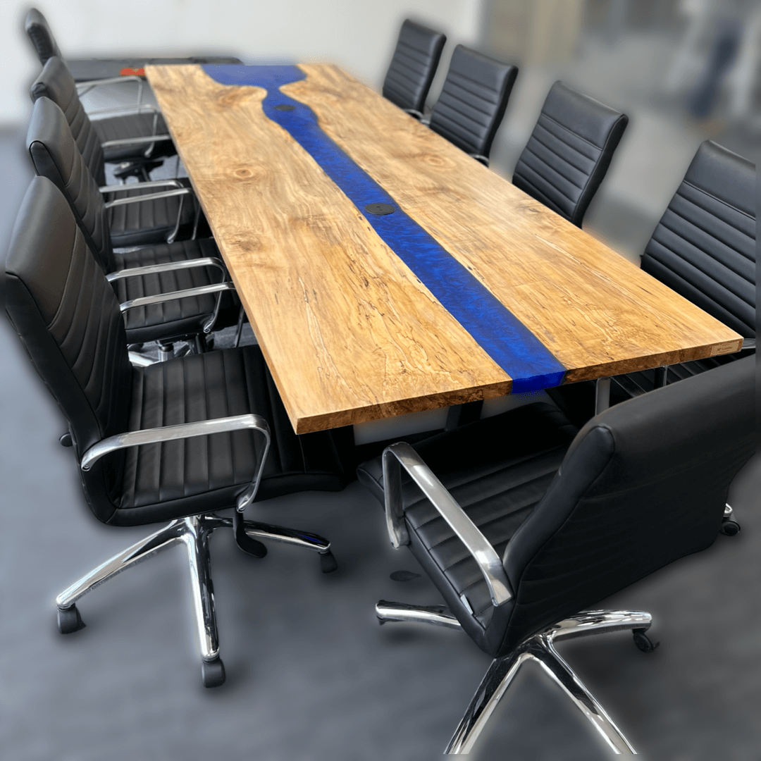 Large epoxy river conference table with blue epoxy and natural wood finish, surrounded by black office chairs in a meeting room.