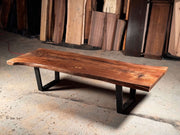 Live edge wood coffee table with black metal legs showcasing natural wood tones and unique grain in rustic setting.
