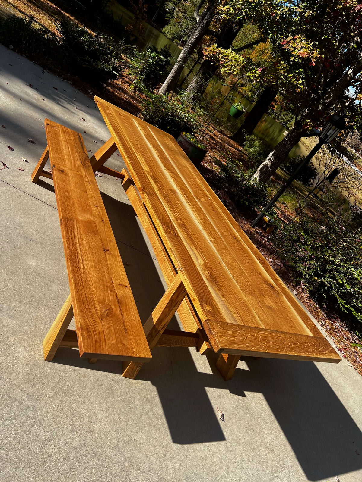Natural wooden Nikko dining table with matching bench, inspired by Japanese sunlight design, set outdoors on a sunny day.