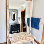 Standing wooden framed mirror enhancing bathroom space with natural elegance and style.