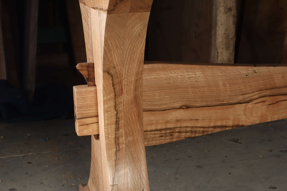 Close-up of solid wood joinery on The Finn Trestle Dining Table base, showcasing its elegant curved design and craftsmanship.