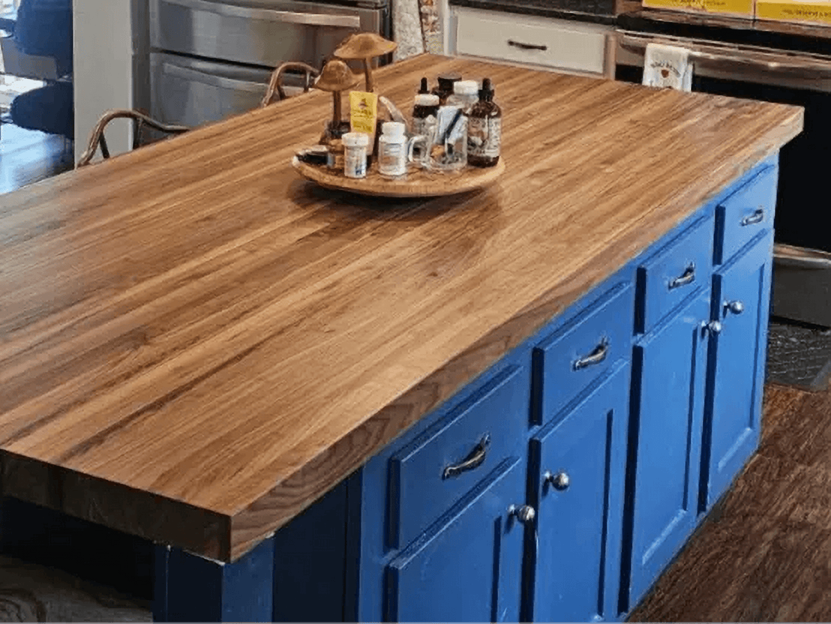 Exquisite hardwood butcher block countertop on blue kitchen island, showcasing luxury and elegance in a modern kitchen setting.