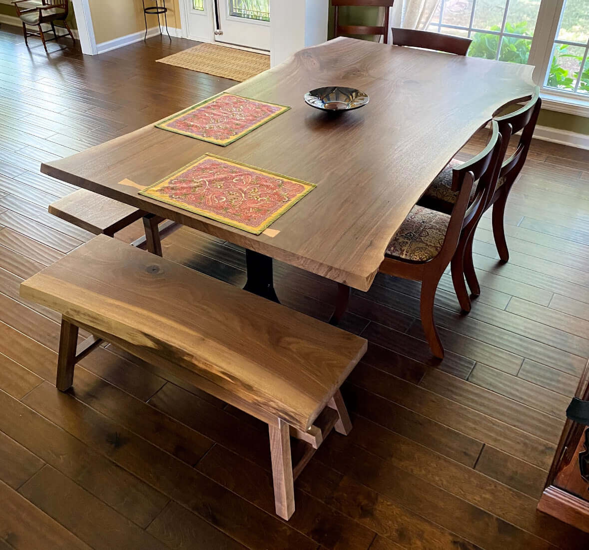 Book-matched live edge table with natural wood beauty, paired with a matching bench and elegant dining chairs.